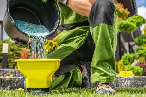 professional landscaper pouring lawn fertilizer into a spreader