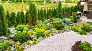 Patio with a landscaped backyard full of beautiful plants, flowers, and trees. 