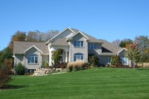 Modern brick home with a large beautiful front yard that is green and lush. 