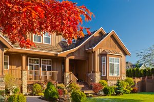 Well kept brown home with a beautifully landscaped front yard with fall foliage. 