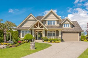 Modern two story house with a beautifully landscaped front yard against a blue sky. 