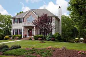 A modern brick home set on a large, beautifully landscaped front yard. 