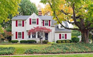 Two story house in the fall with red shutters 