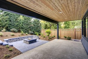 Landscaped backyard with a covered patio and fire pit area. 