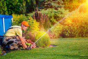 A professional landscape employee adjusting a residential irrigation system. 